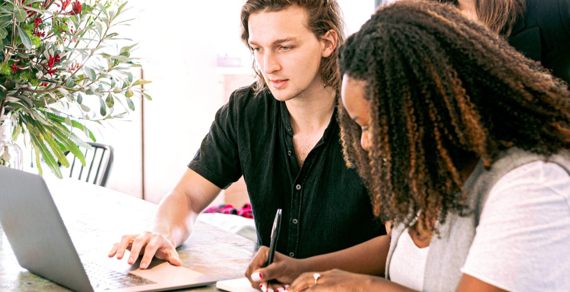 a-person-writing-and-a-person-on-a-laptop-working